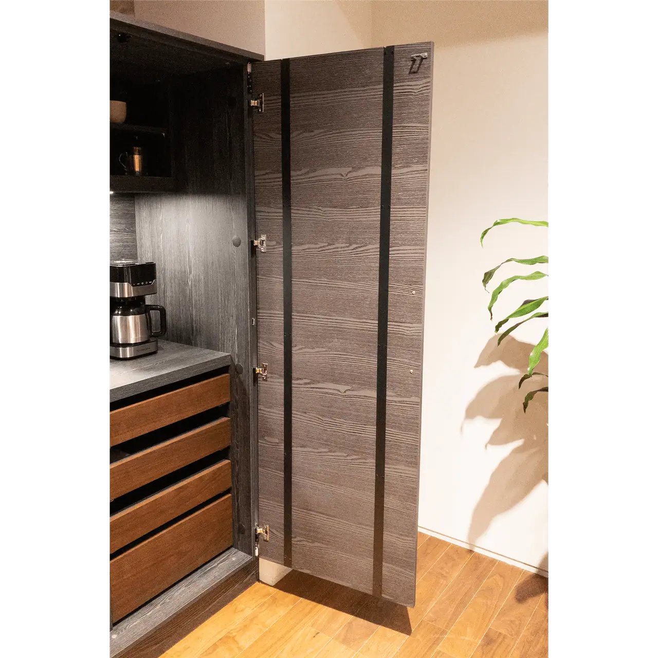 Open dark wood cabinet with coffee maker inside.