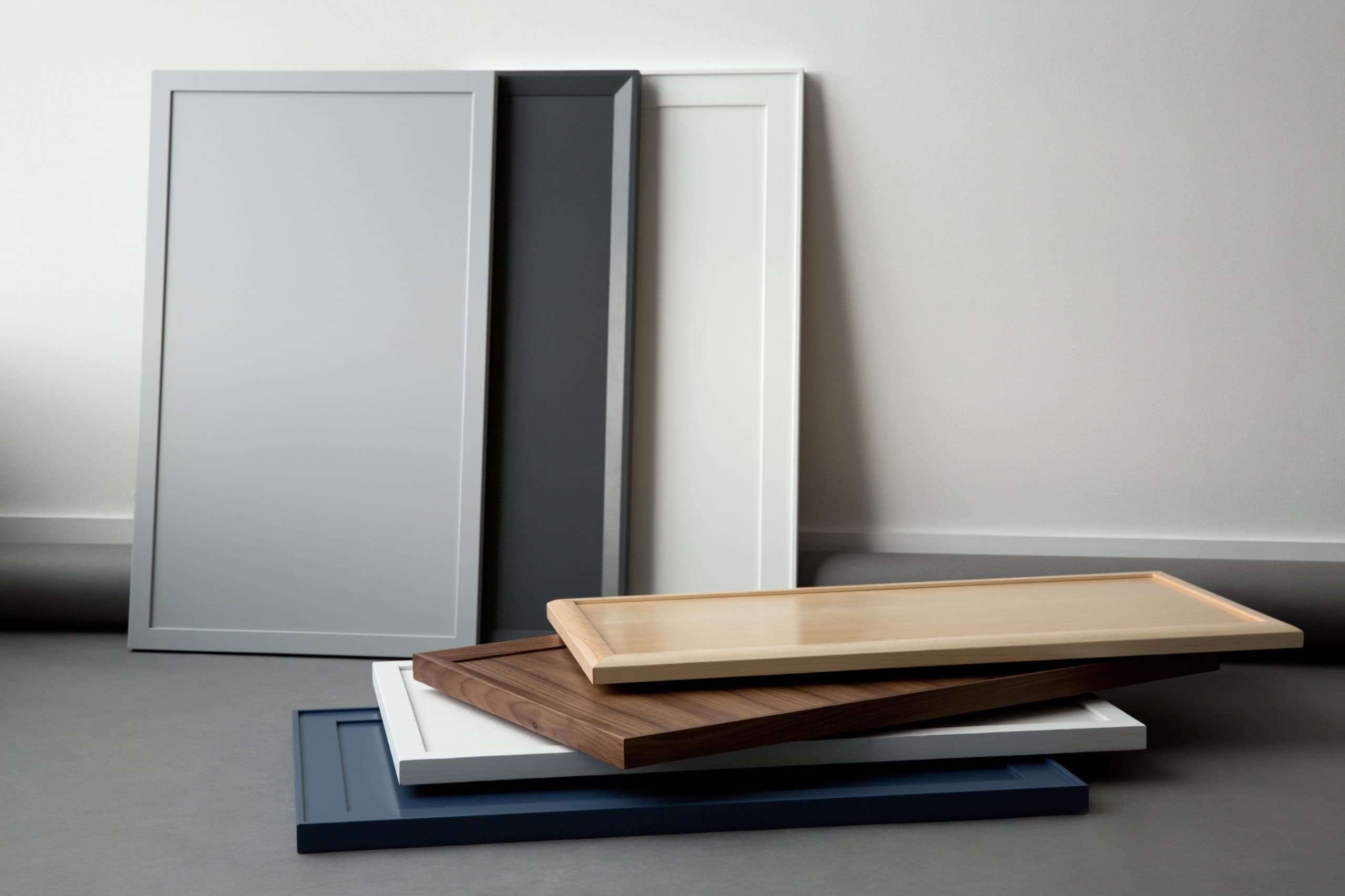 Stacked cabinet doors in various colors and materials.