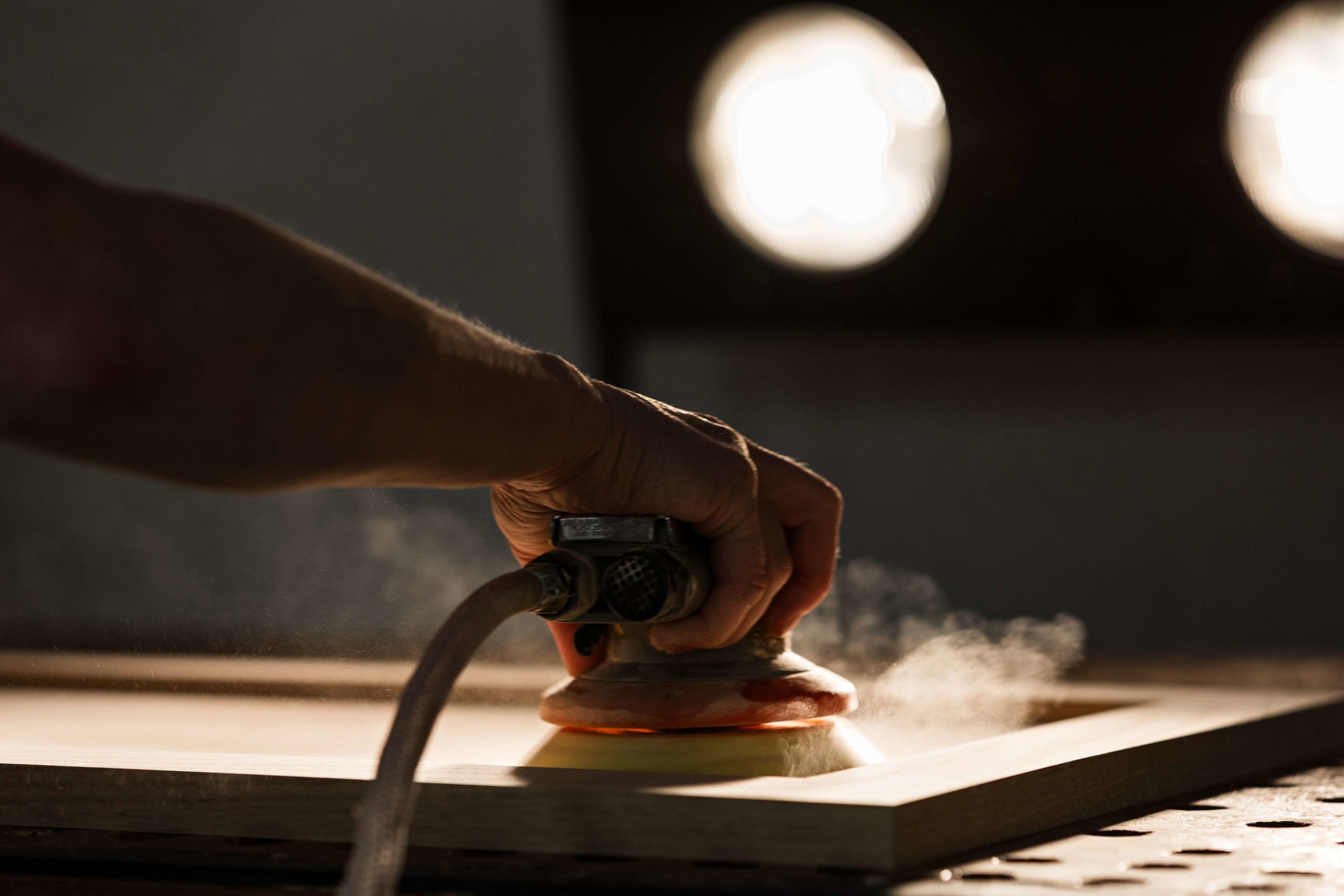 Hand sanding wooden surface with sander tool.