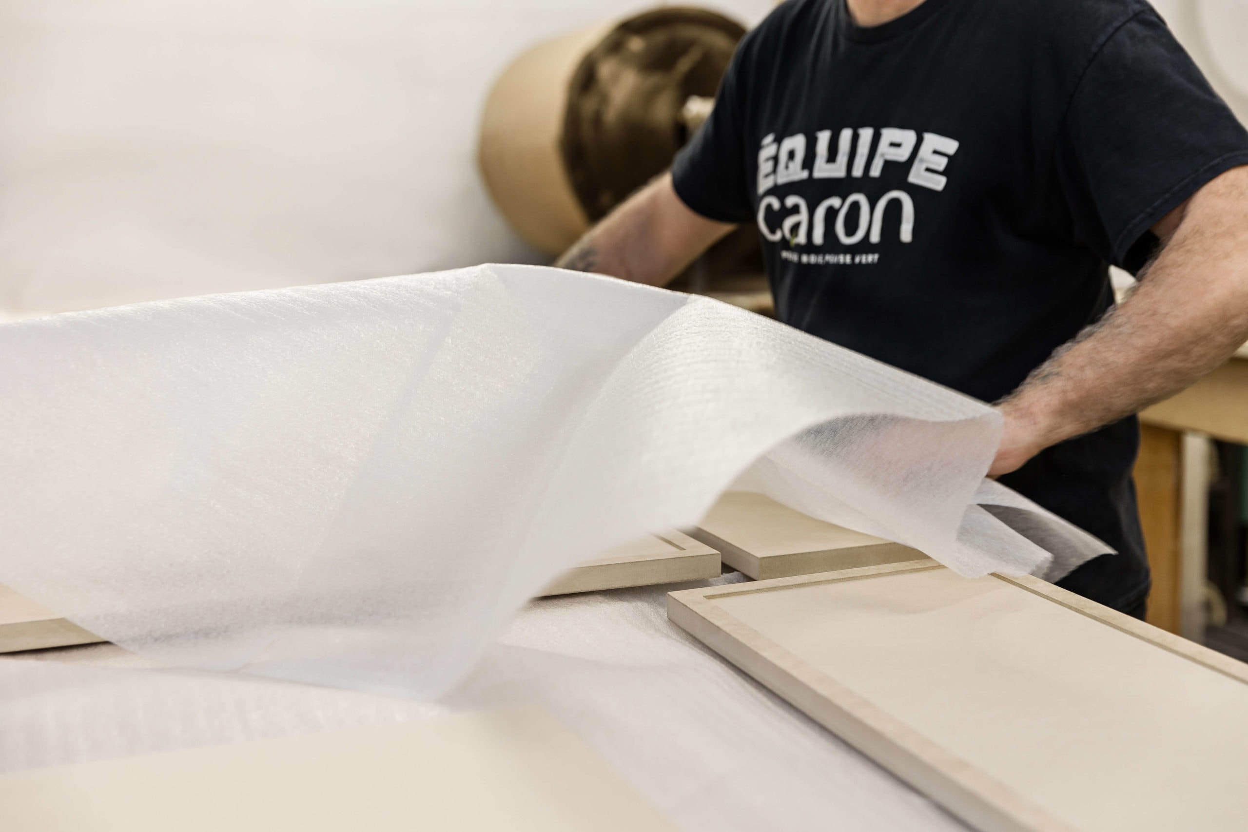 Person wrapping wood with protective material